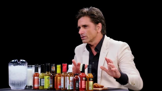 S21:E09 - John Stamos Falls Out of His Chair While Eating Spicy Wings